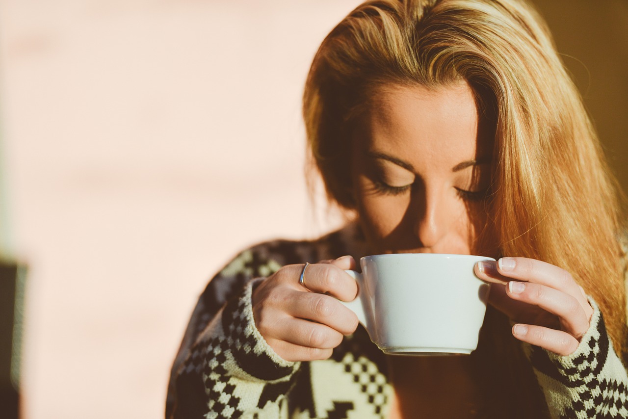 Ragazza che indossa un maglione invernale e beve una tisana calda.