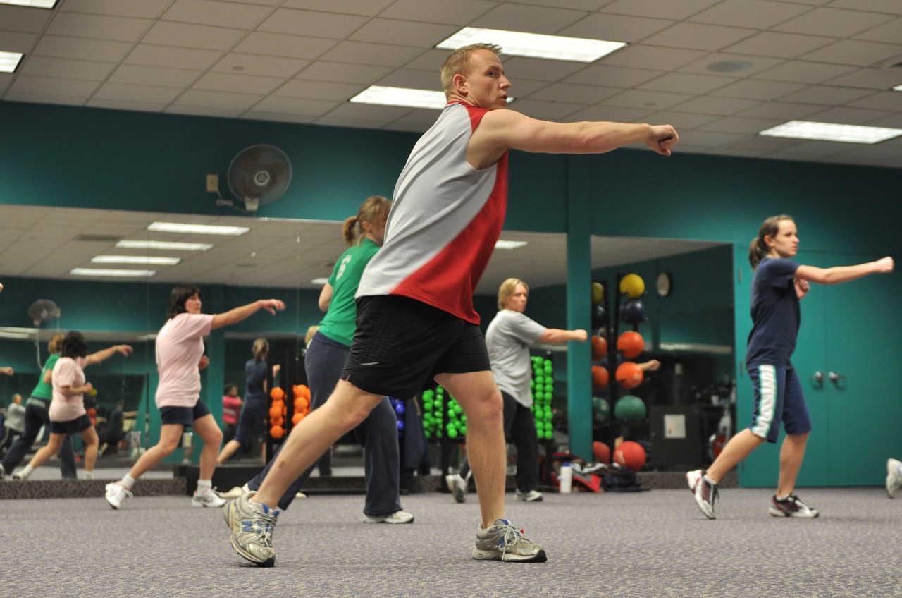 Rappresentazione di una sala fitness in cui l'istruttore sta tenendo un corso di ginnastica aerobica utile al dimagrimento.