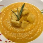 Foto della Ricetta della Crema di Zucca con Polenta croccante e erba cipollina, impiattata con un rametto di rosmarino