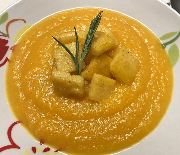 Foto della Ricetta della Crema di Zucca con Polenta croccante e erba cipollina, impiattata con un rametto di rosmarino