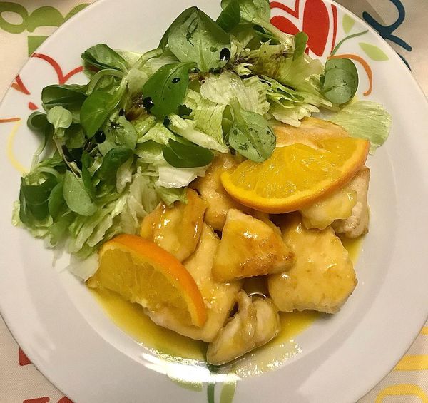 Foto della Ricetta del Pollo alla Arancia, ricoperto da una leggera infarinatura e impiattato con della insalata cruda