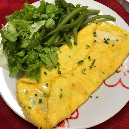 Foto della Ricetta della Omelette al Formaggio, condita con Erba Cipollina, Curcuma e impiattata con della Insalata Fresca