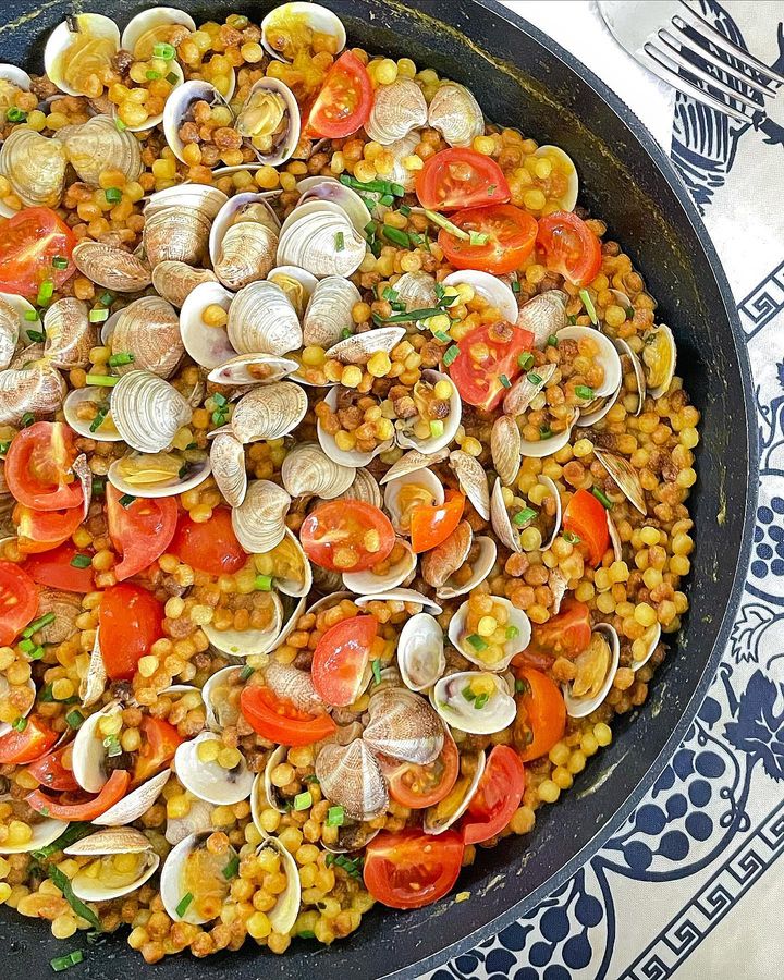 Foto della ricetta di Fregola con le vongole, con brodo vegetale, pomodorini ciliegini, limone e aglio.