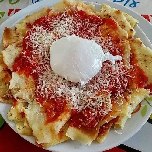 Foto della ricetta di Pai frattau con spicchi di pane carasau, sugo di pomodoro e pecorino sardo.