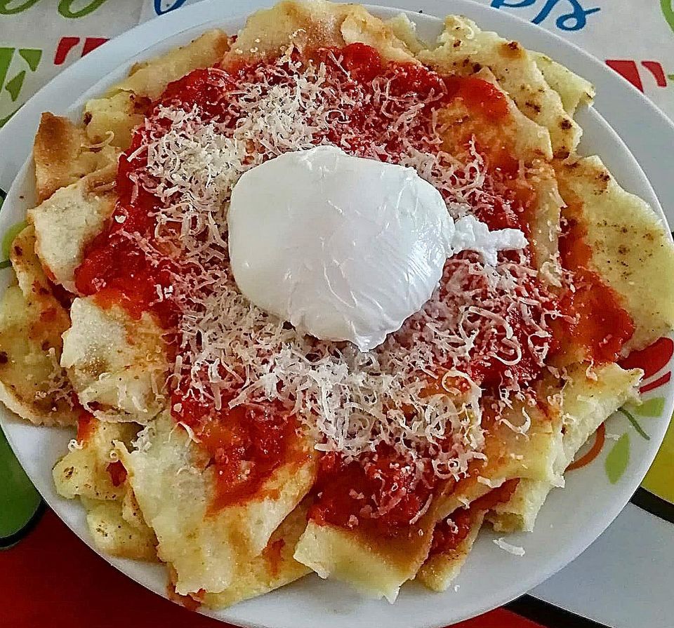 Foto della ricetta di Pai frattau con spicchi di pane carasau, sugo di pomodoro e pecorino sardo.